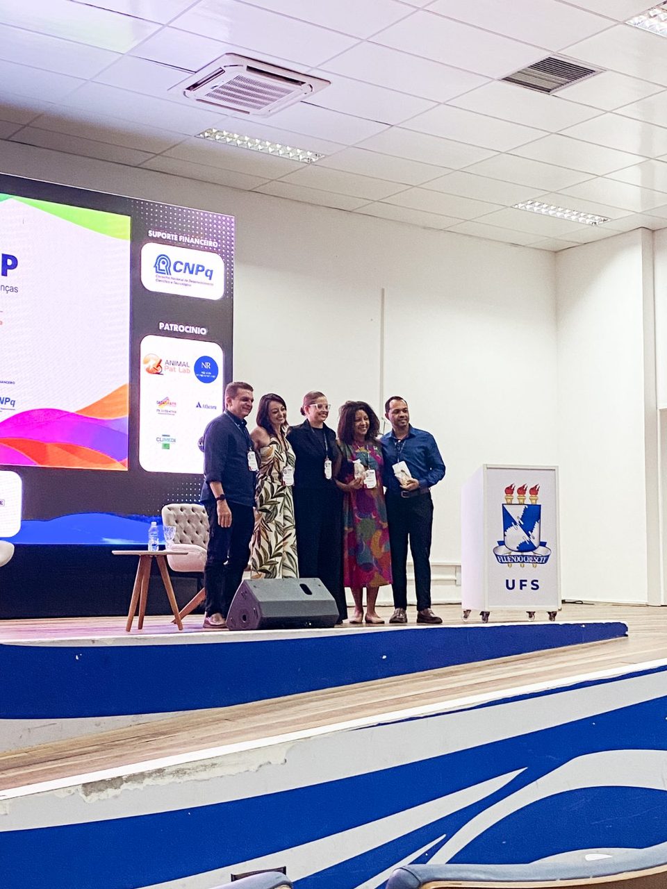 Cinco integrantes da Rebrapi no palco, durante a mesa-redonda da rede no V Simpósio Nordestino de Doenças Infecciosas e Parasitárias